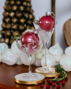 Two clear Christmas ornaments sit in martini glasses filled with ice. The ornaments are filled with a glittery vodka cranberry cocktail Ornamentini Cocktail Recipe, Christmas Drink In Ornament, Ornament Cocktail Recipe, Ornament Cocktail Ideas, Christmas Cocktail Garnish, Ornamentini Cocktail, Ornaments Drinks, Christmas Ornament Drinks, Ornament Cocktail