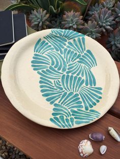 a blue and white plate sitting on top of a wooden table next to sea shells