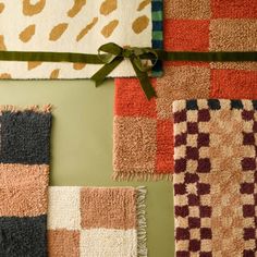 four different colored rugs tied together with a green ribbon on the wall behind them