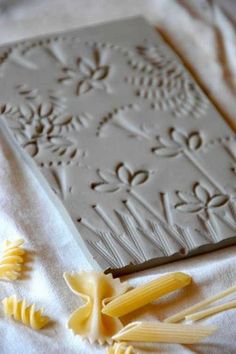 the pasta is being made on top of the paper with flowers and leaves around it