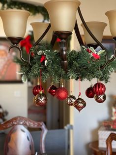 a chandelier with christmas decorations hanging from it's sides and lights on