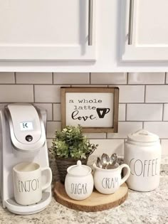 the coffee maker is next to two mugs and a sign that says, i love you