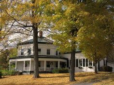 a white house surrounded by trees in the fall