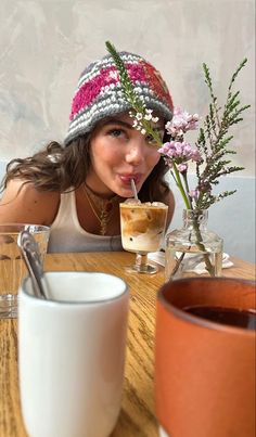 a woman sitting at a table with a flower in her mouth and a cup of coffee