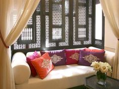 a white couch sitting under a window next to a table with flowers on top of it