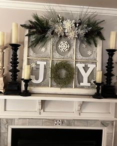 a fireplace mantel with candles, wreaths and snowflakes hanging on it