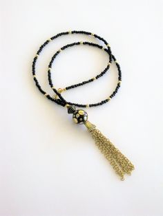 Bohemian Style black and gold beaded necklaces, handmade by Ralston Originals. These beautiful tassel necklaces come in your choice of 3 different Styles. I made the tassels with gold metal chain, and a large antique gold cap. I made the first necklace (pictures 1-3), with a large black bead with gold metal dots, and a black bead with gold stripes. The beaded chain is made with black seed beads, and gold acrylic beads. This necklace is 28 inches long, and has a lobster clasp. I made the second n Adjustable Beaded Chain Tassel Necklace As Gift, Tassel Necklace With Round Beads For Gifts, Elegant Beaded Tassel Necklace For Festivals, Lariat Beaded Necklace With Tassels For Gift, Bohemian Long Necklace With Black Round Beads, Gift Lariat Beaded Necklace With Tassels, Black Tassel Jewelry For Festival, Black Tassel Necklace With Adjustable Fit, Adjustable Black Tassel Necklace