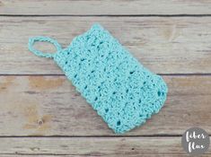 a blue crocheted pouch sitting on top of a wooden table next to a bottle opener