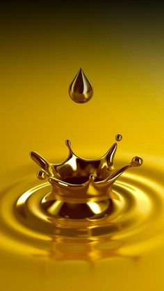 a yellow liquid splashing into the water with a droplet in it's center