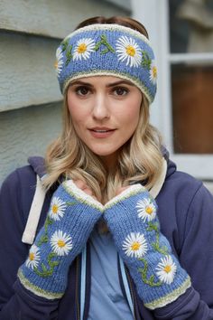 a woman wearing a knitted headband with daisies on it and holding her hands to her face