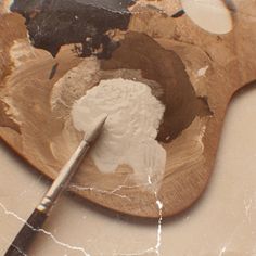 a wooden spoon with white powder in it and a paintbrush on the table next to it