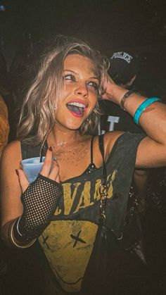 a woman with her hand on her head at a concert, making the peace sign