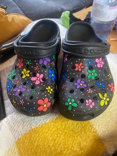 a pair of black clogs with flowers painted on them sitting on a blanket