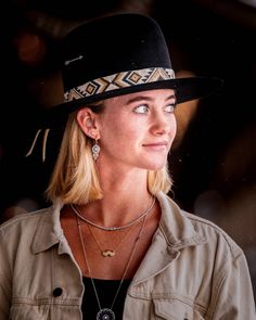 a woman wearing a black hat and tan jacket looking off to the side with her eyes wide open