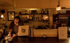 a man sitting at a bar writing on a piece of paper in front of him