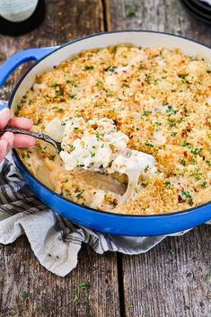 a blue casserole dish filled with macaroni and cheese, garnished with parsley