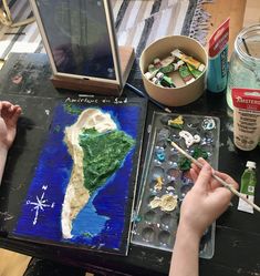 a person is painting on a table with paint and other items around it, including an easel