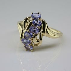 10K Yellow Gold Tanzanite Cocktail ring, 6 oval faceted lilacs ovals 2.5x4mm set vertical in a serpentine line bypass shank goes high and low, Ring size 8, 2.6 grams, Circa 1985 SKU # BB272R16 Most rings are sizable for a small fee. If the ring you are considering is the incorrect size contact us for a quote. This listing contains photographs of the actual item you will receive. Our items are in excellent condition with little or no signs of wear and many are one of a kind pre-owned estate finds Fine Jewelry Lavender Oval Jewelry, Lavender Oval Fine Jewelry, Gold Coin Ring, Coin Ring, Purple Band, Fine Jewelry Designers, Blue Topaz Ring, Gold Coins, Topaz Ring