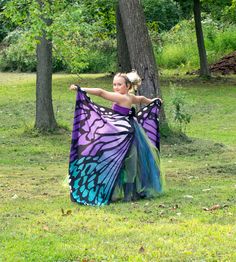 a woman in a purple and blue dress holding a butterfly shawl over her shoulder