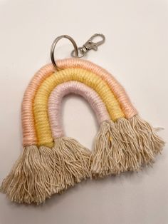 a rainbow keychain with tassels hanging from it's side on a white surface