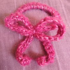 a pink crocheted bow on top of a bed