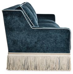 a blue velvet couch with fringe trim on the arm and back, against a white background