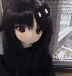 a close up of a doll with long black hair and a cat head on it's head