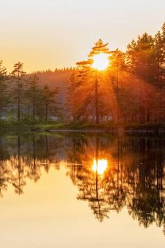 the sun is setting over a small lake