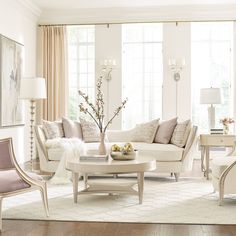 a living room filled with white furniture and lots of window sill space next to a fire place