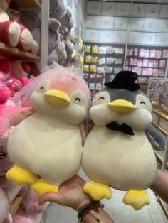 two stuffed penguins sitting on top of each other in front of a store display shelf