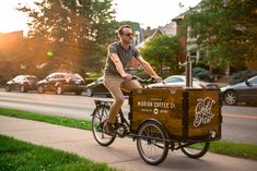 a man riding a bike with a coffee cart attached to the front and back wheels