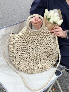 a woman sitting on a chair holding a bag with flowers in it