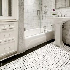 a white bathroom with black and white tile flooring, a sink, toilet and bathtub