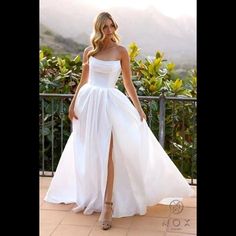 a woman in a white dress standing on a balcony