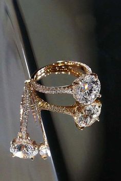 two gold rings with diamonds on them sitting on top of a black piece of paper