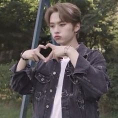 a young man making a heart shape with his hands while standing in front of a street sign