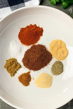 several different types of spices on a white plate