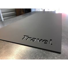 the word travel is engraved on an aluminum sheet that sits on top of a metal table