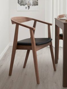 a wooden chair sitting next to a table with a black leather seat on top of it