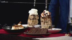 two desserts sitting on top of a table with people in the background looking at them