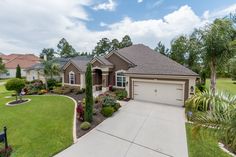 a house with landscaping in front of it and trees around the driveway area on either side