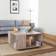 a living room with a couch, coffee table and laptop on the floor in front of it