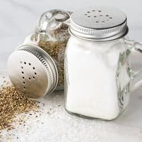 a salt and pepper shaker sitting on top of a table next to some spices