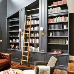 a living room filled with lots of bookshelves next to a couch and chair