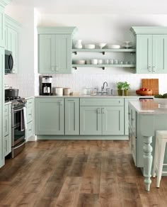 a kitchen with white cabinets and wooden floors