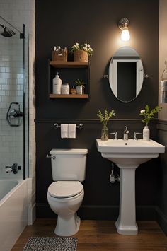 a white toilet sitting next to a sink in a bathroom under a mirror and light