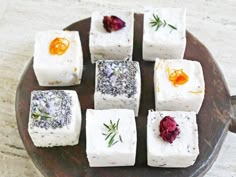 small squares of food sitting on top of a wooden plate with dried herbs and orange slices