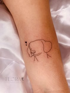 a small dog tattoo on the left arm and leg, with a heart in it's mouth