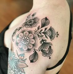 a close up of a woman's shoulder with flowers and leaves tattooed on it