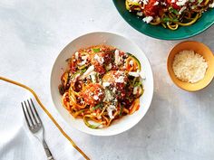 two plates of spaghetti with meat and vegetables on the side, next to a bowl of rice